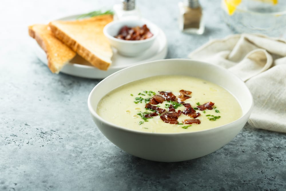 A bowl of creamy chowder served with crackers and parsley garnish.